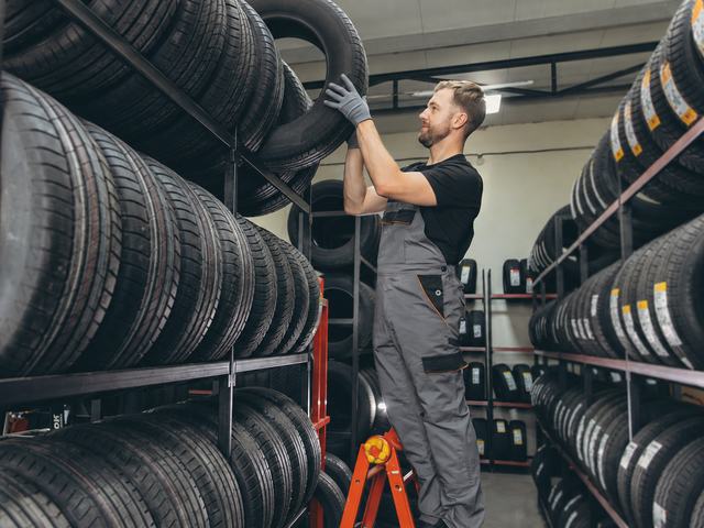 Fitter lifting a tyre down from the racking